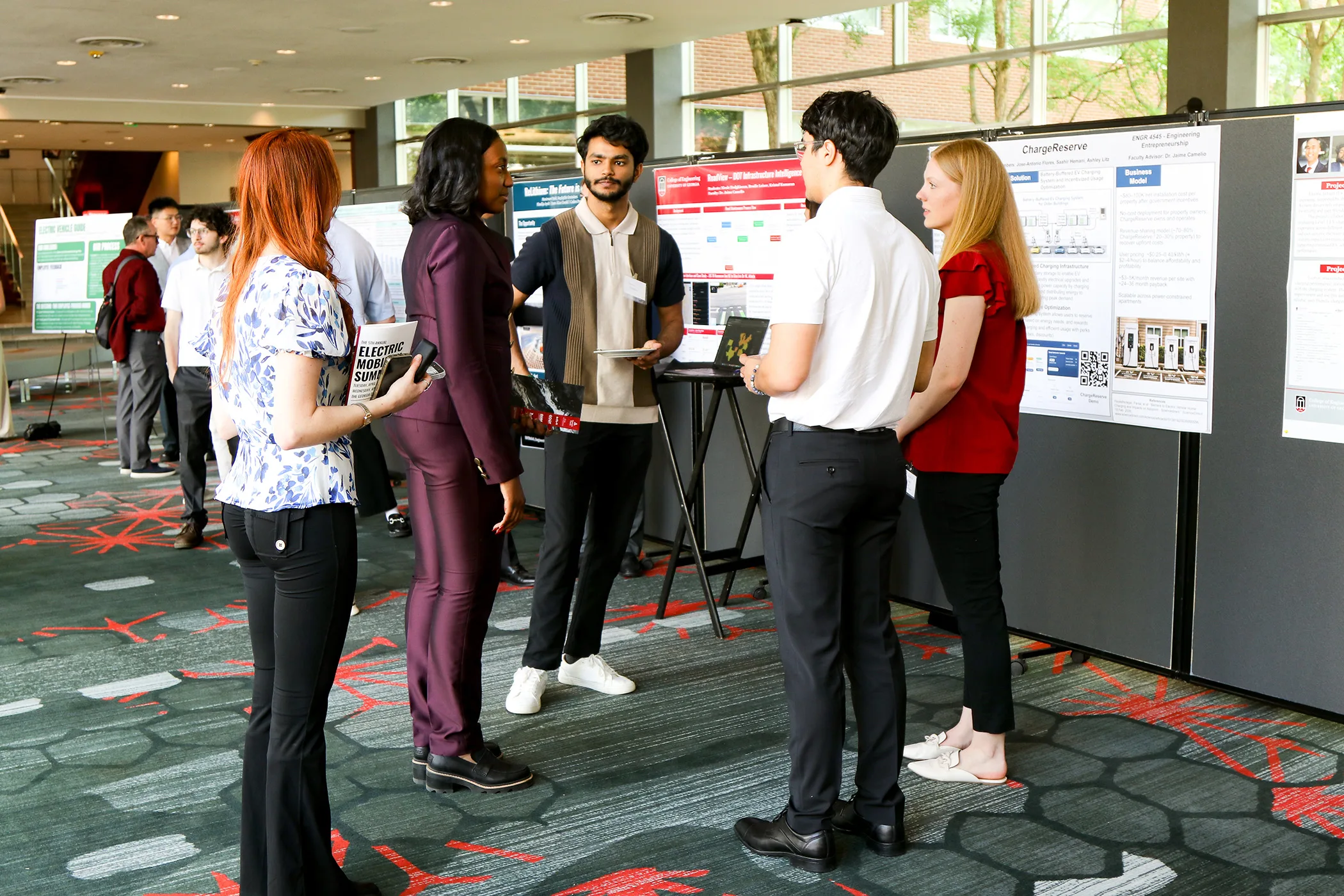People stand in a small group discussing research posters displayed on boards during a conference poster session.